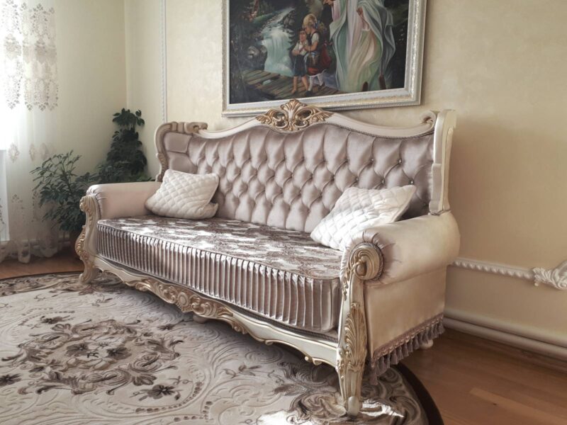 Класичний диван з каретною стяжкою та різьбленими елементами в інтер'єрі вітальні